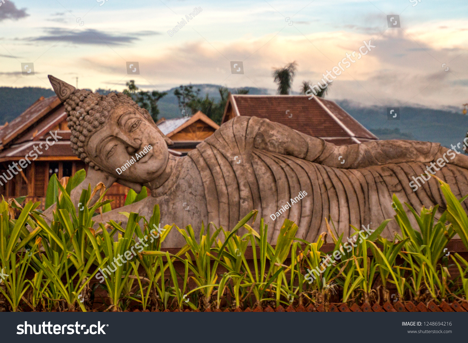 Traditional Reclining Buddha near Chinese Theravada Dai Temple with View of Evening Sky. Classical Buddhist Iconography in Jinghong China (Xishuangbanna Yunnan Province China).