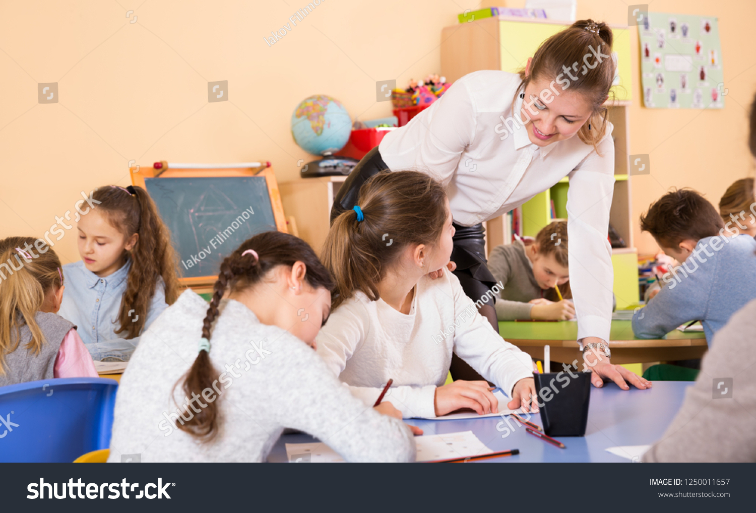 young female teacher and pupils working at the c