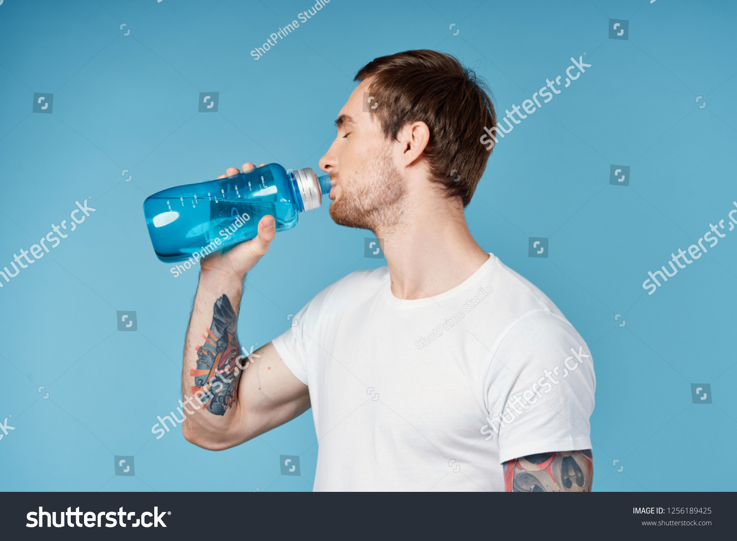 A man is drinking from a blue bottle             