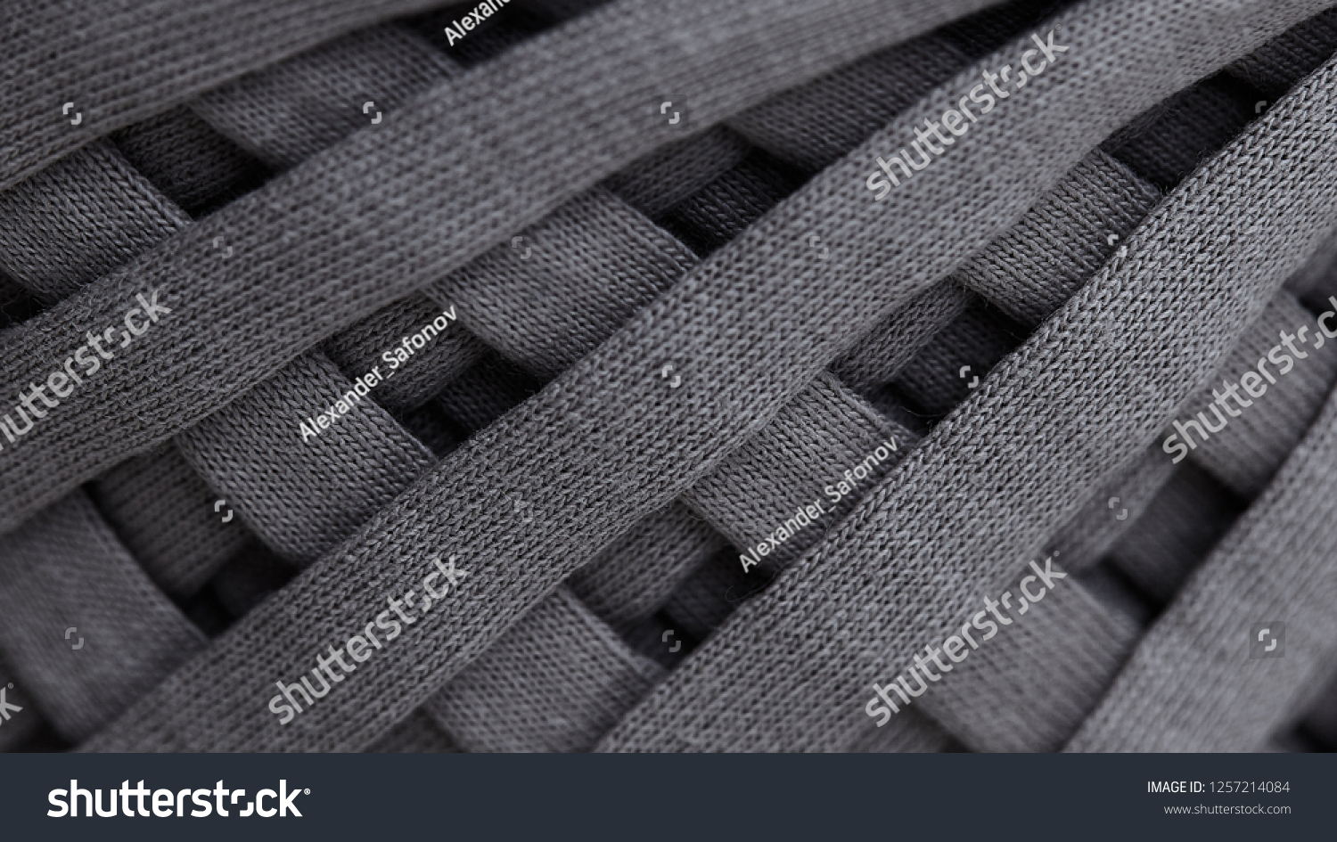 Skein of gray knitted yarn close-up. macro photography background texture pattern weave fiber textile fabric. strips of fabric are interwoven on a reel.