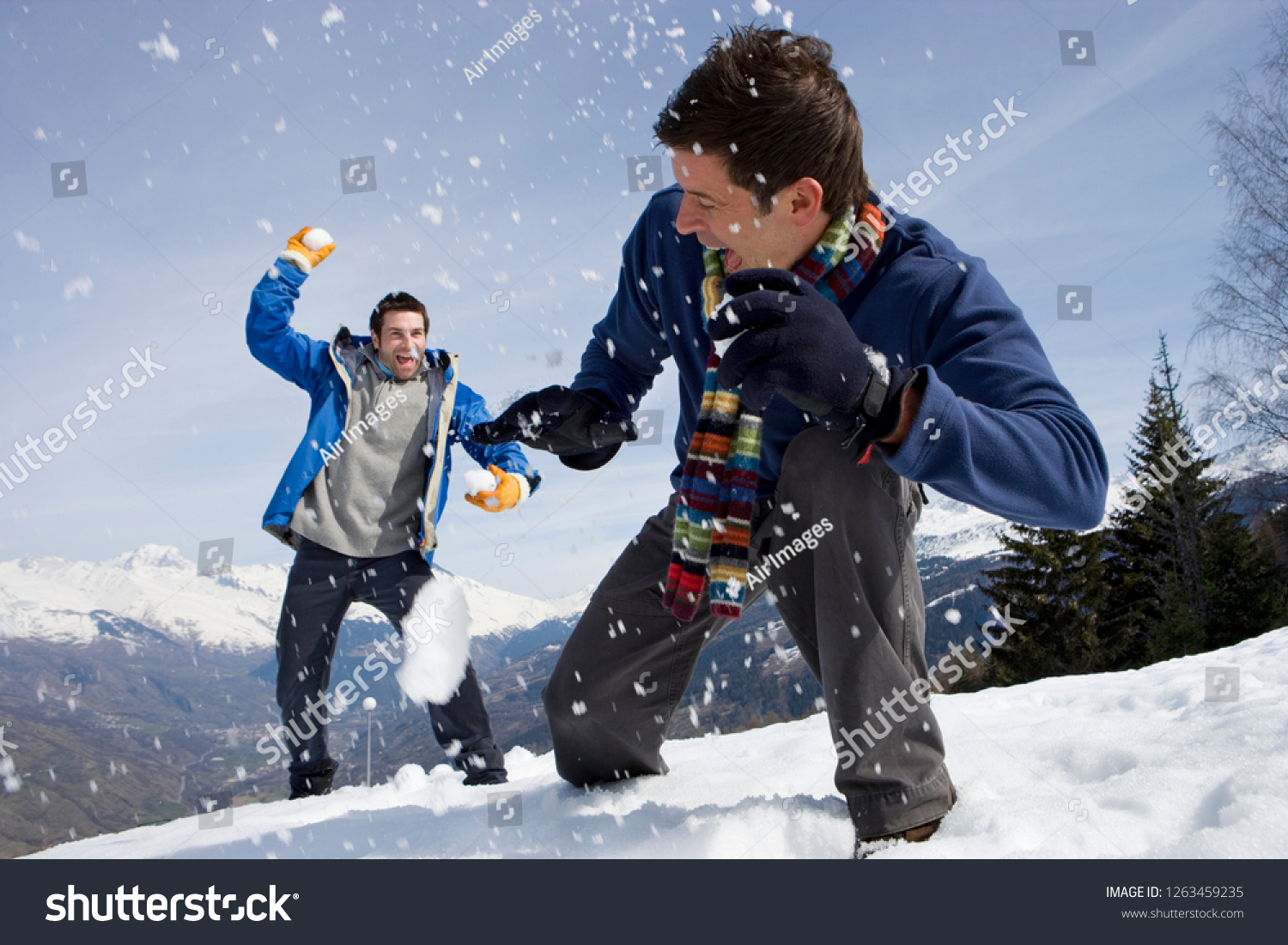 Young men having snowball fight in snow on winter vacation