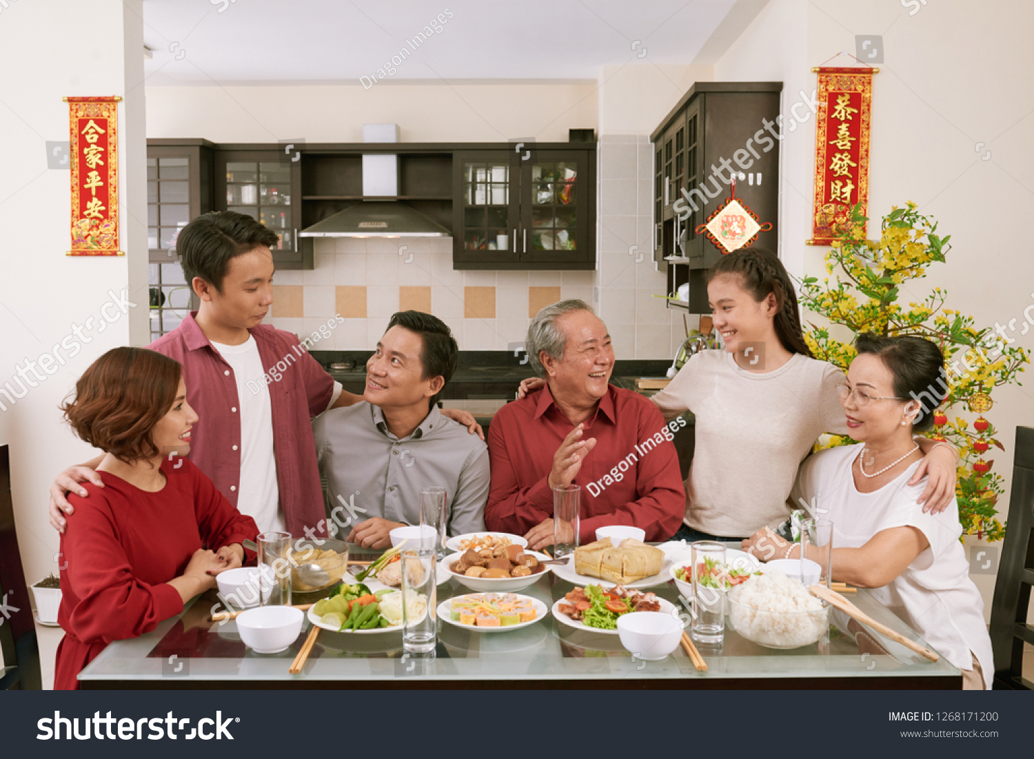 Big Vietnamse family enjoying traditional dinner and celebrating Lunar New Year  couplets with best wishes for coming year in the background