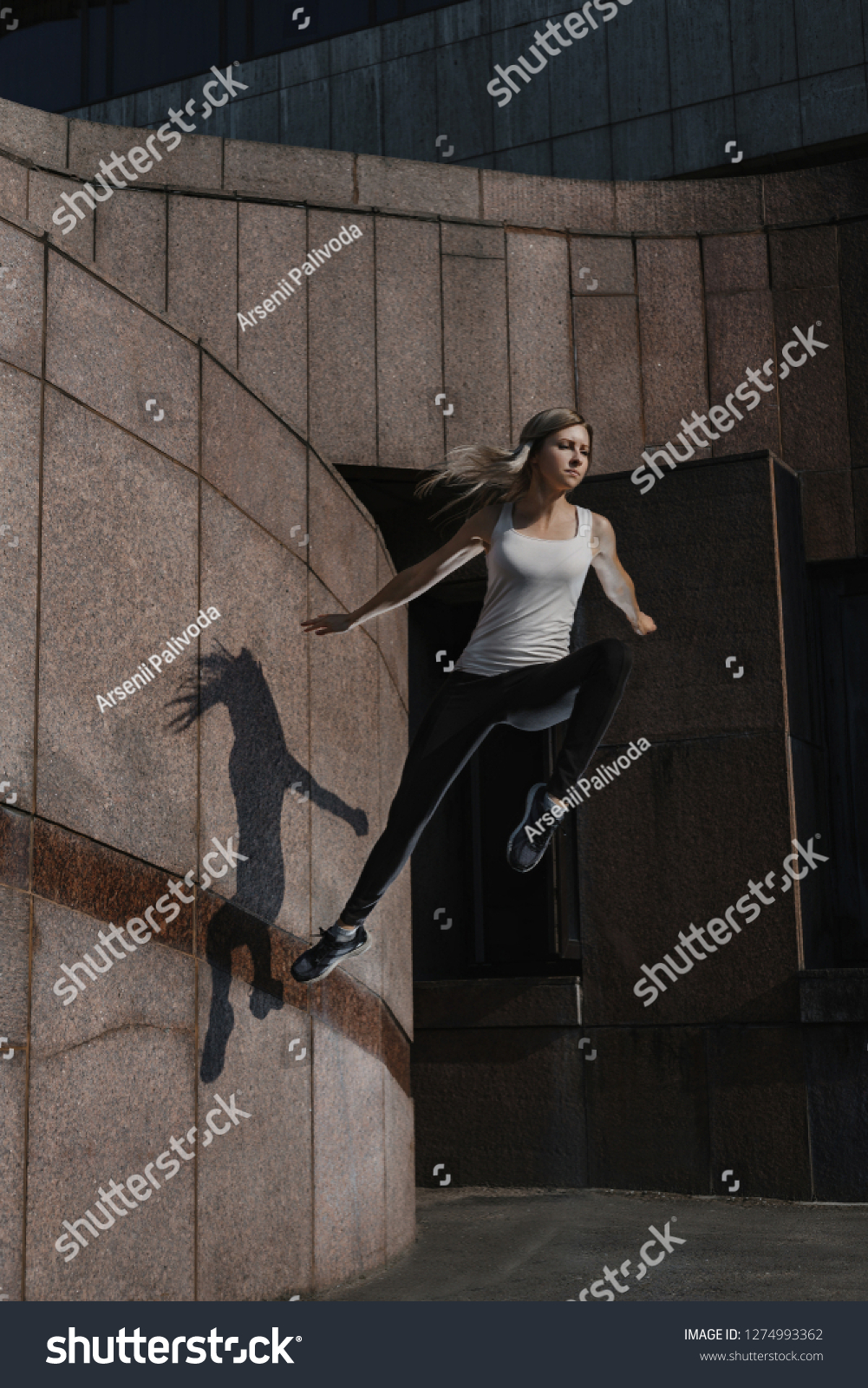 Young sporty woman doing parkour in city. The girl is engaged in freerunning.