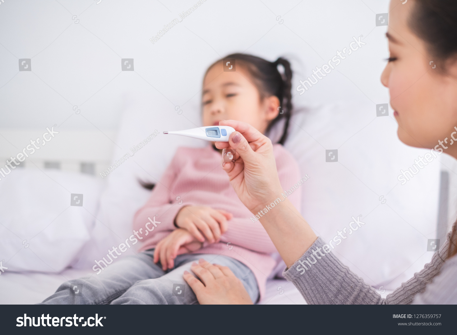 Mother using thermometer with her girl kid daughter for sickness and fever