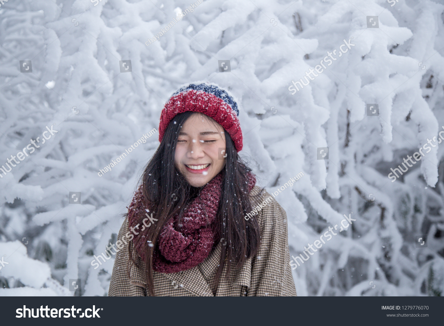 Portrait of woman with red wool hat feeling very happy and cold under snowy weather at Shin-hotaka Japan Alps.