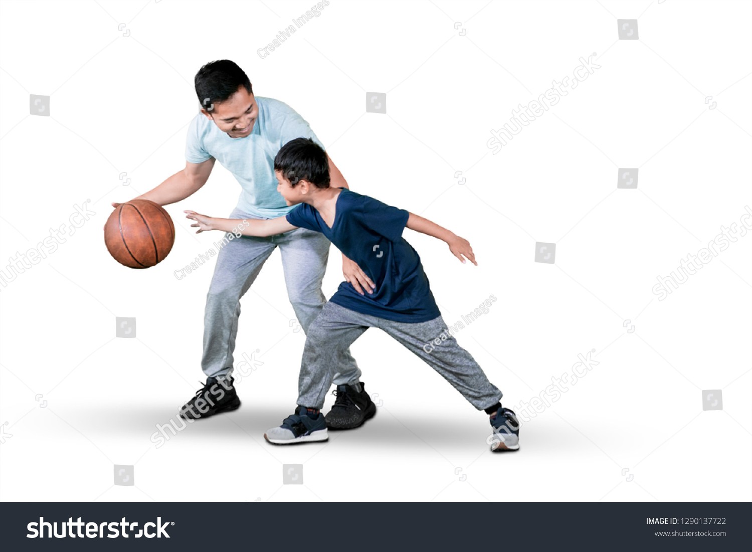 Picture of a young man and his son playing basketball while exercising in the studio  isolated on white background