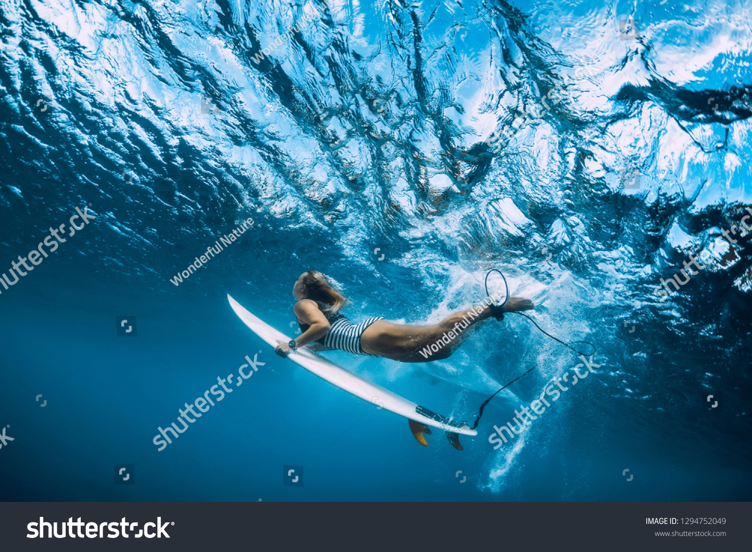 Surfer woman with surfboard dive underwater with ocean wave.