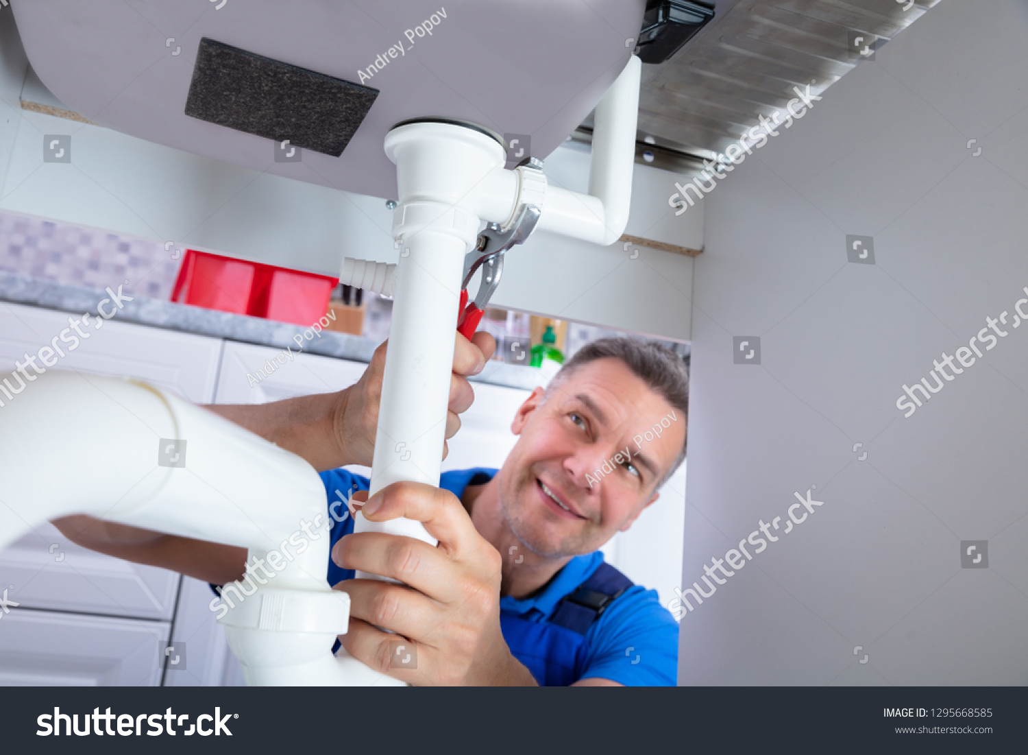 front view of male plumber repairing sink pipe with adjustable