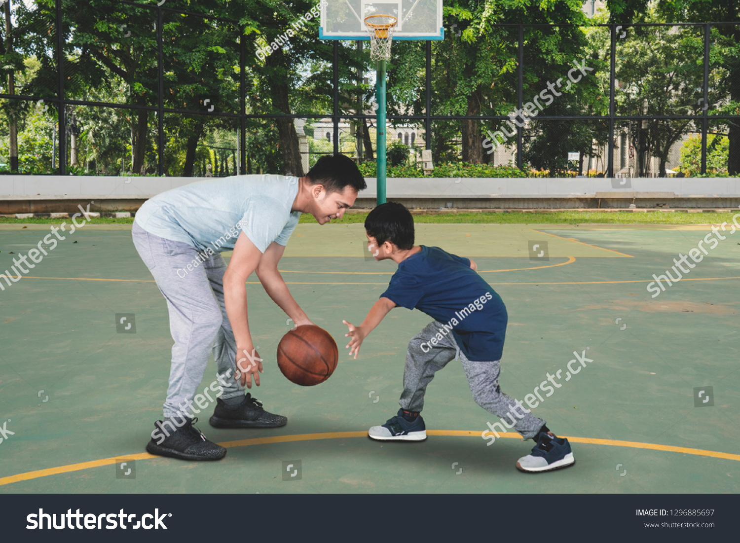 Picture of a young man and his son exercising with basketball in the field