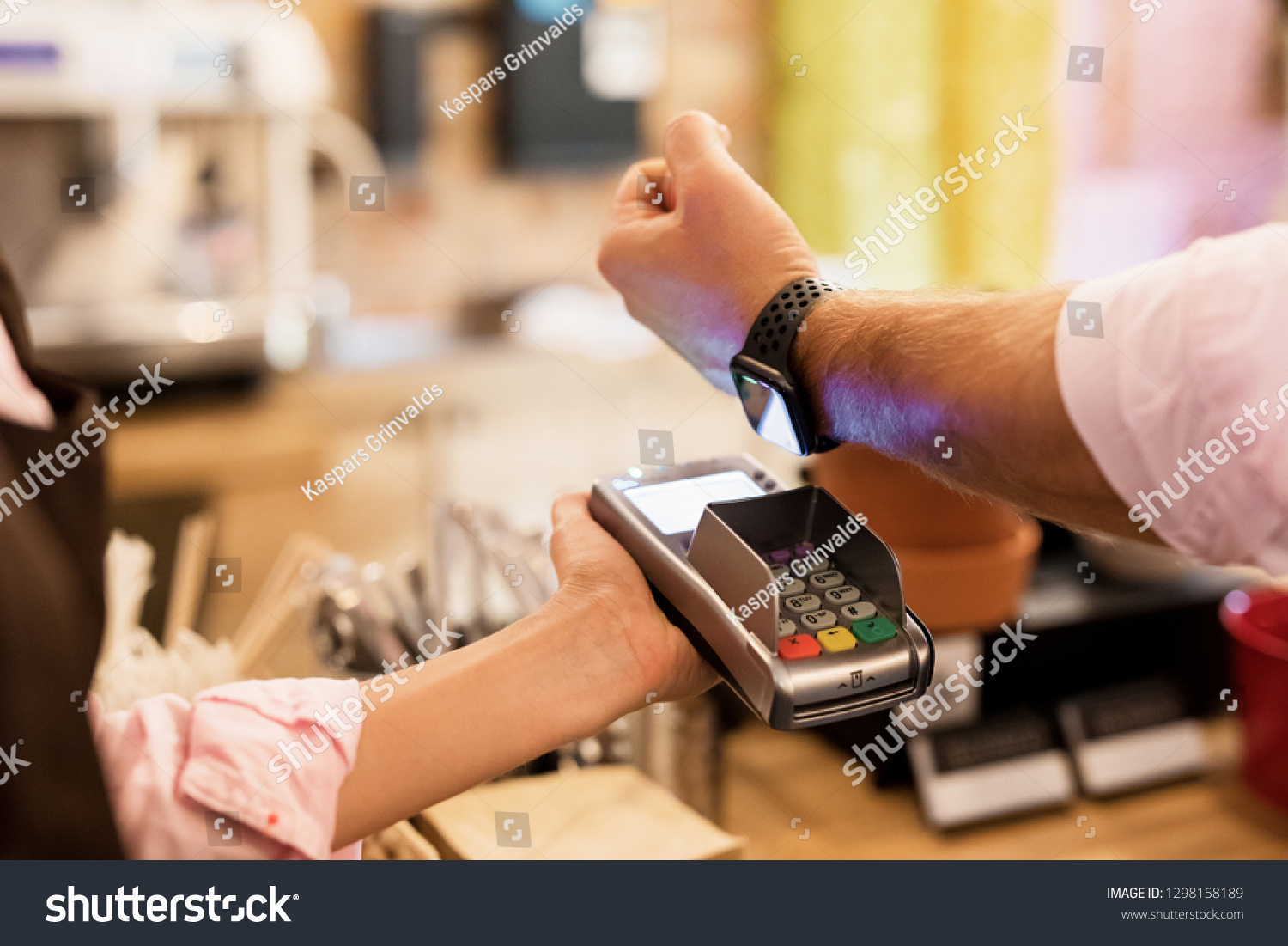 Person paying at cafe with smart watch wirelessly on POS terminal