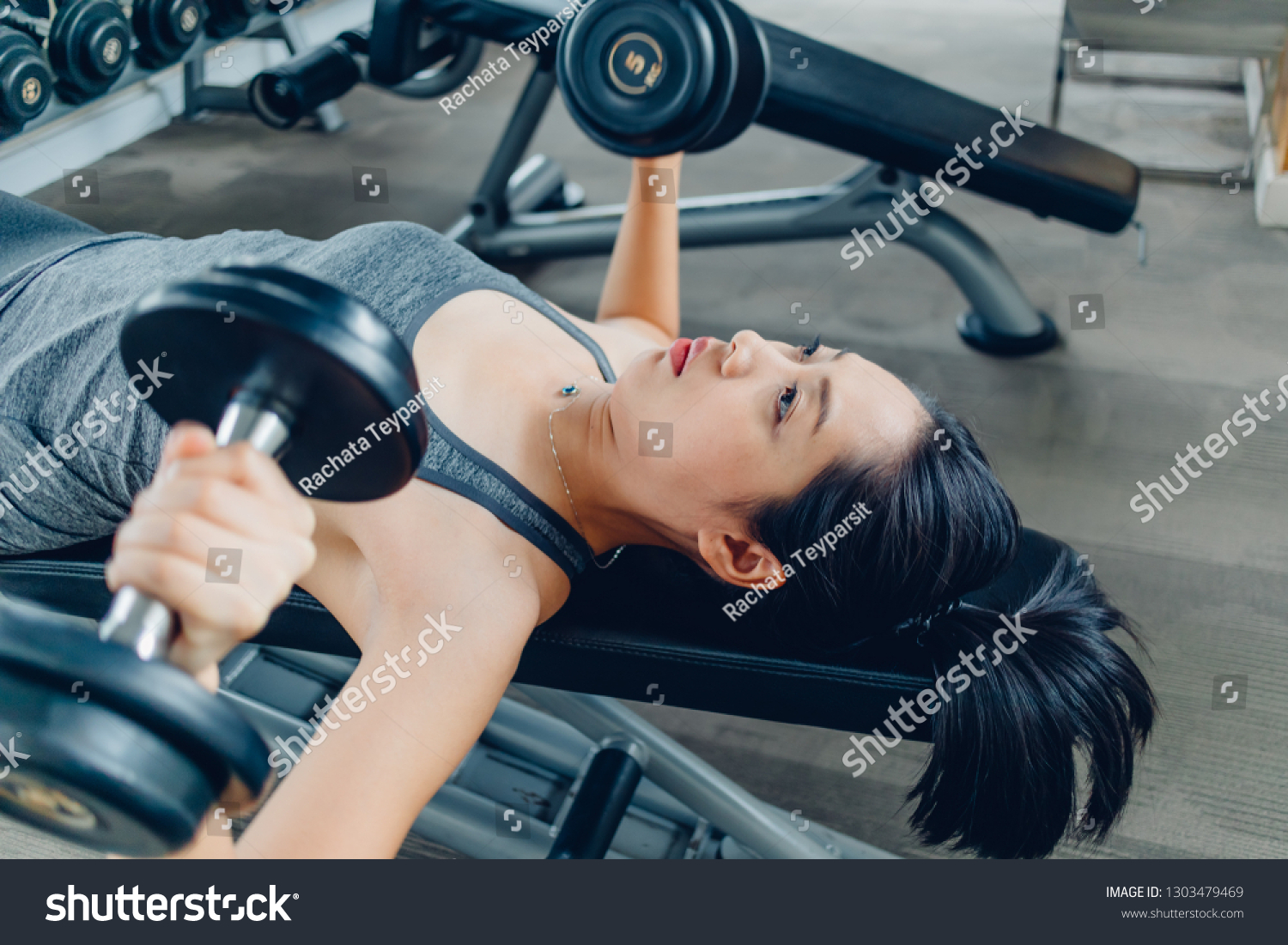 Asian woman workout for dumbbell bench press in the fitness gym.
