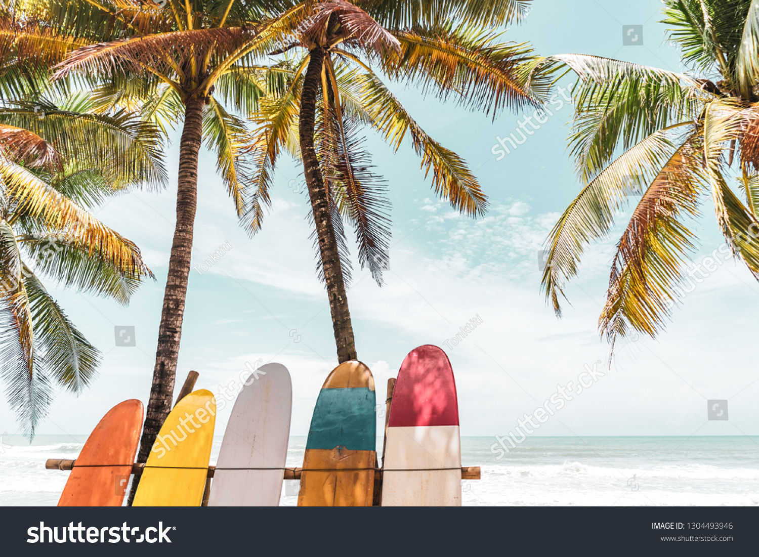 Surfboard and palm tree on beach background. Travel adventure sport and summer vacation concept. Vintage tone filter effect color style.