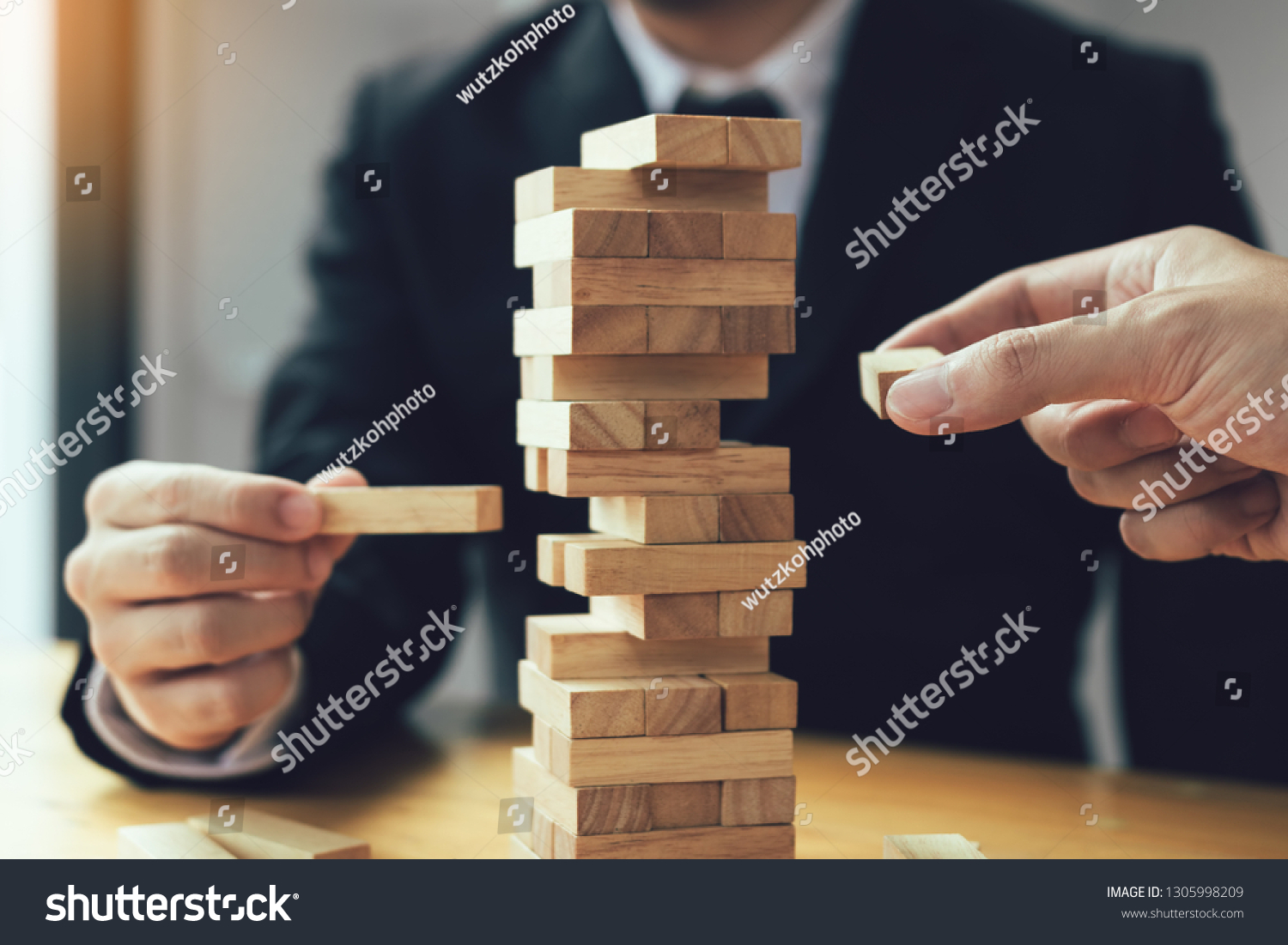 Strategic thinking and risk by business people pulls wooden blocks from the group.