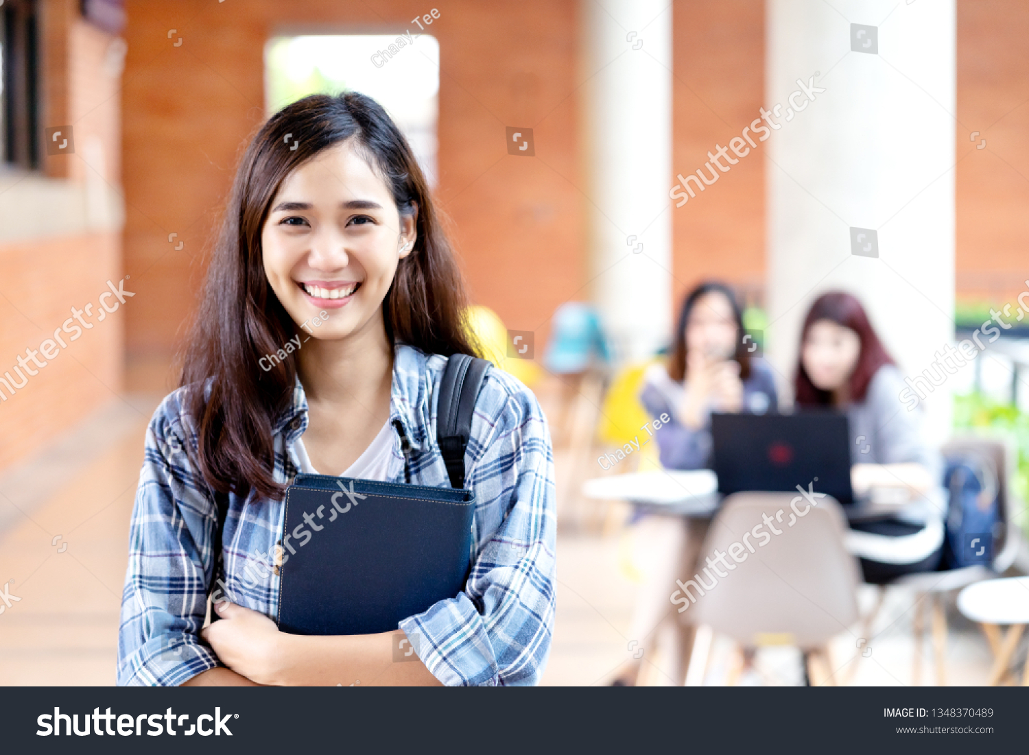 Headshot of young happy attractive asian student smiling and looking at camera with friends on outdoor university background. Asian woman in self future education or personalized learning concept.