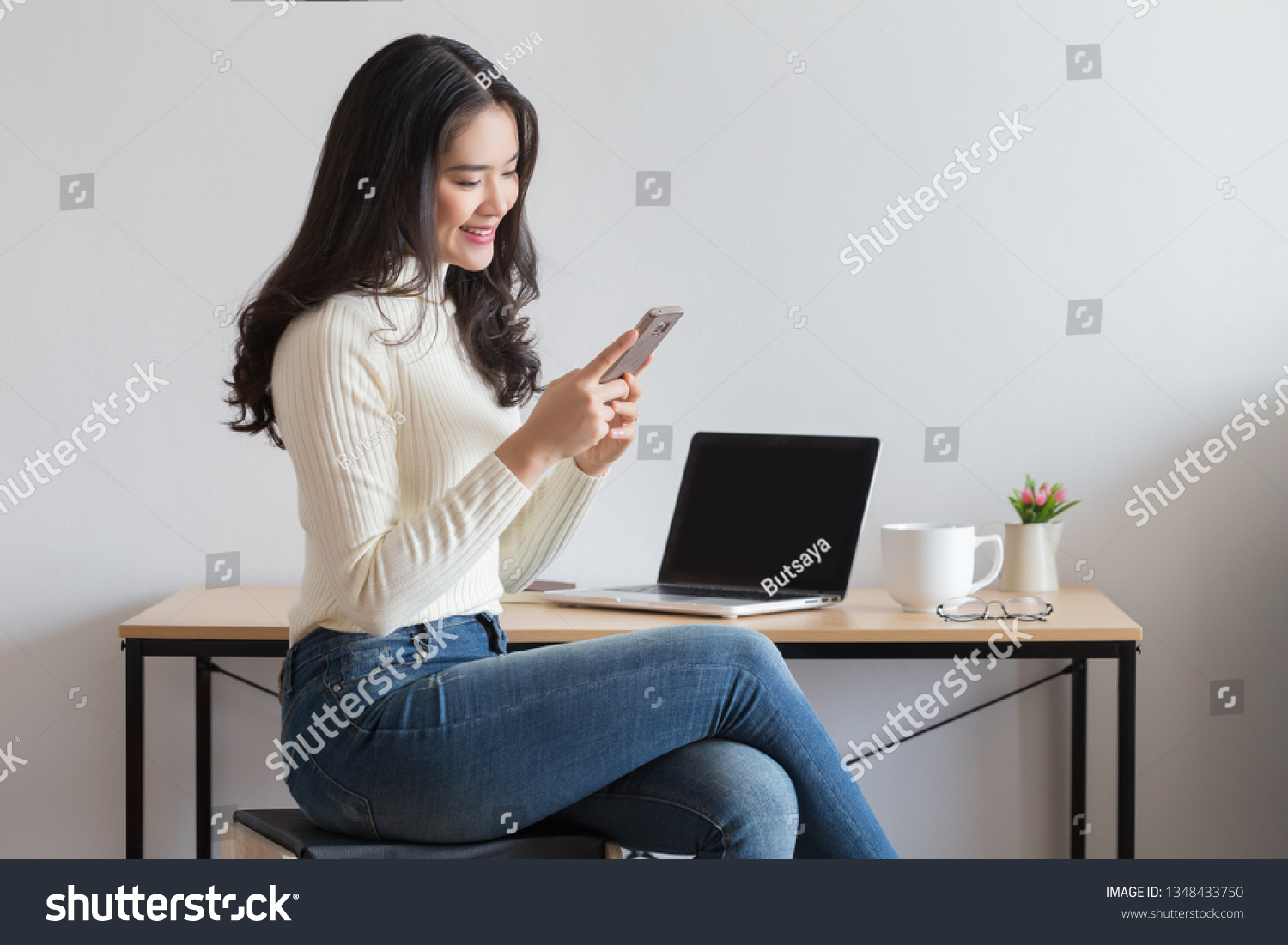Young happy Asian woman using smart phone at the office.