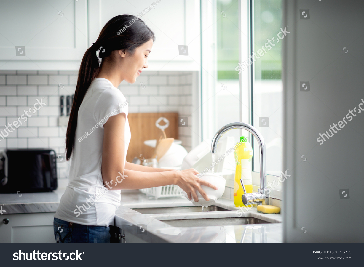 Asian lady wash a dish in kitchen room