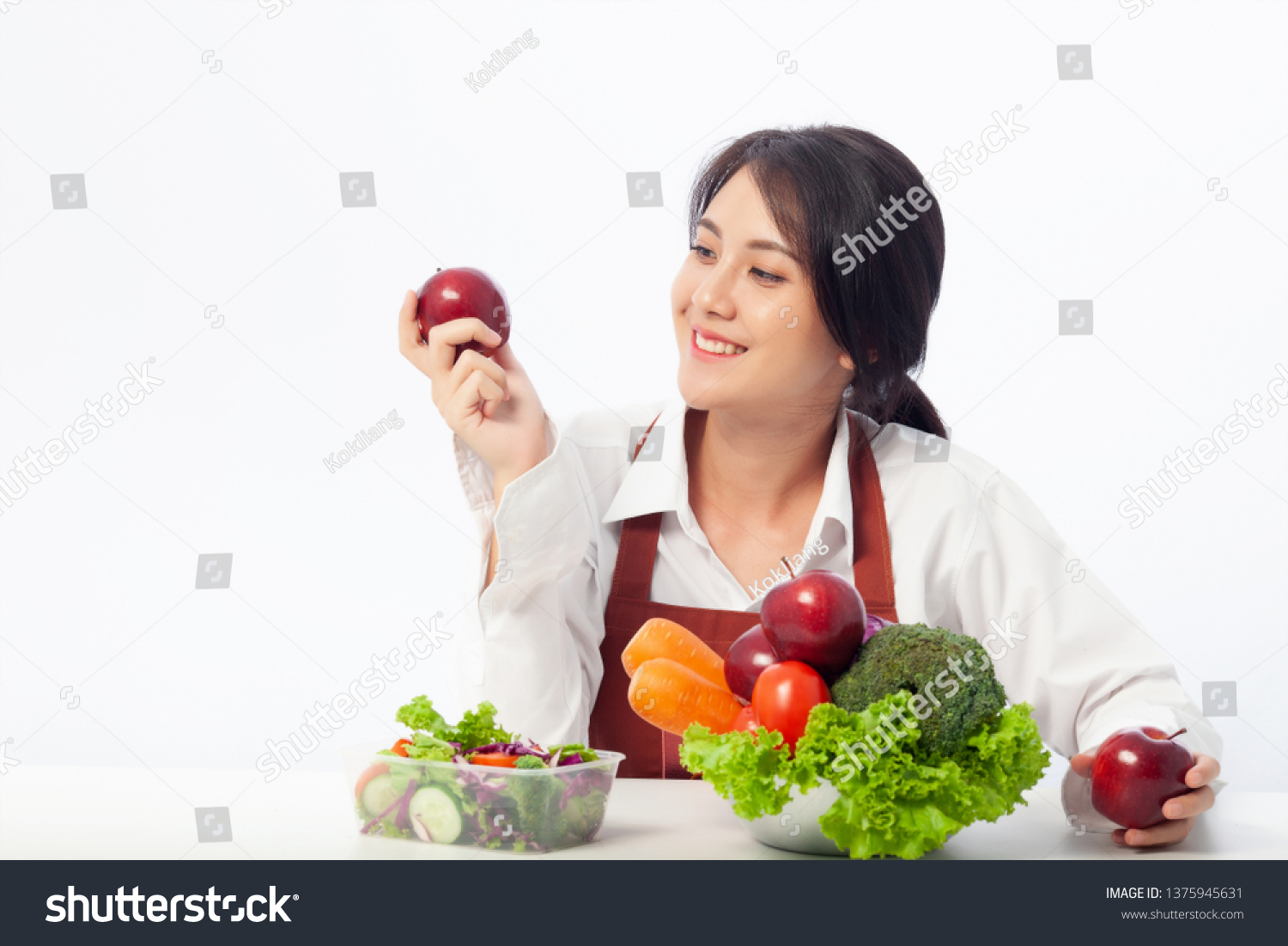 Asian young woman is happy holding fresh fruit apple with vegetables   Healthy  Fresh food  Clean eating recipes to fuel body from the inside out concept.