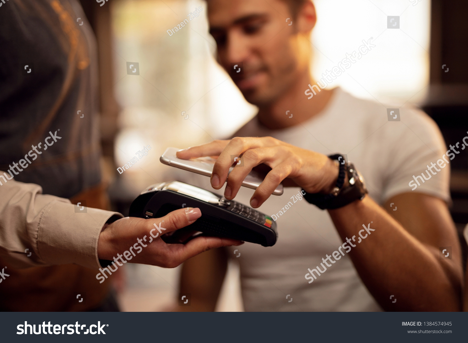 Close up of guest using smart phone while making contactless payment in a pub. 