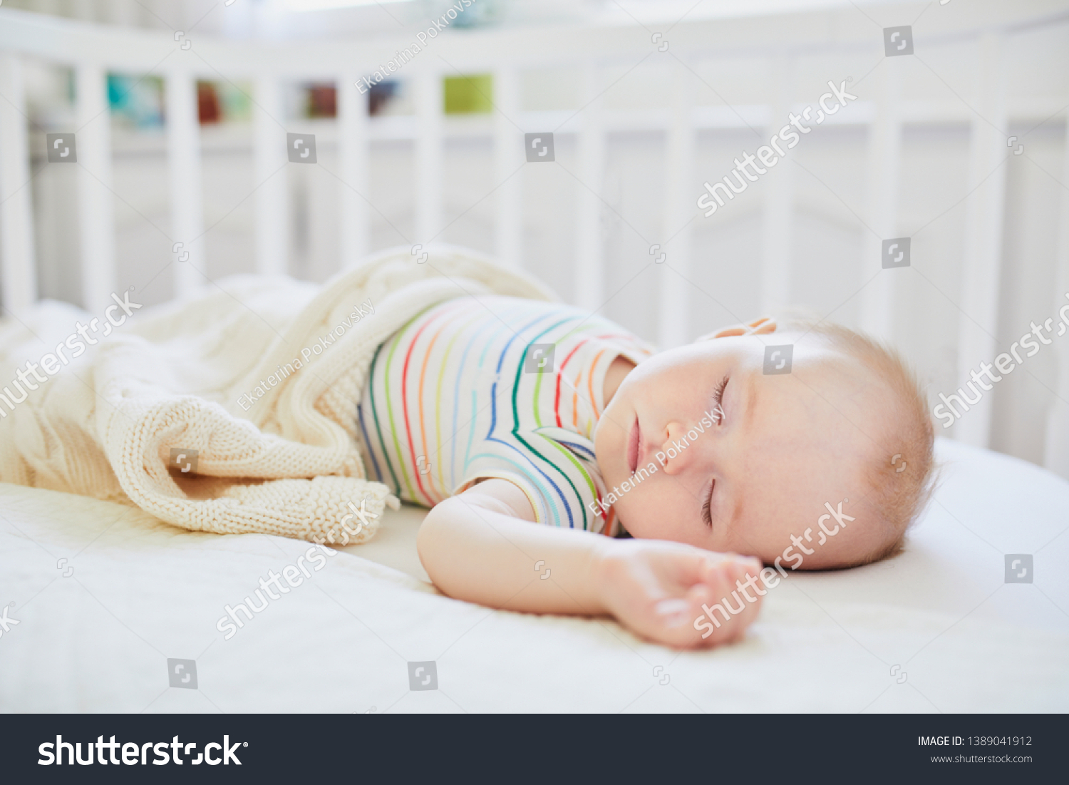 Adorable baby girl sleeping in cosleeper crib attached to parents' bed