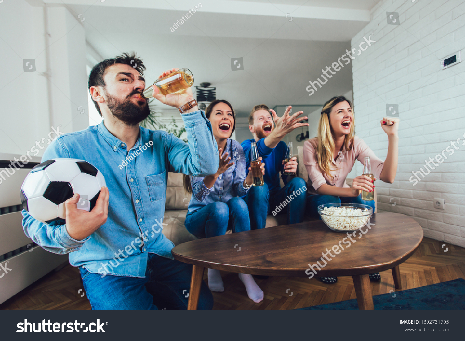Happy friends or football fans watching soccer on tv and celebrating victory at home.Friendship sports and entertainment concept.