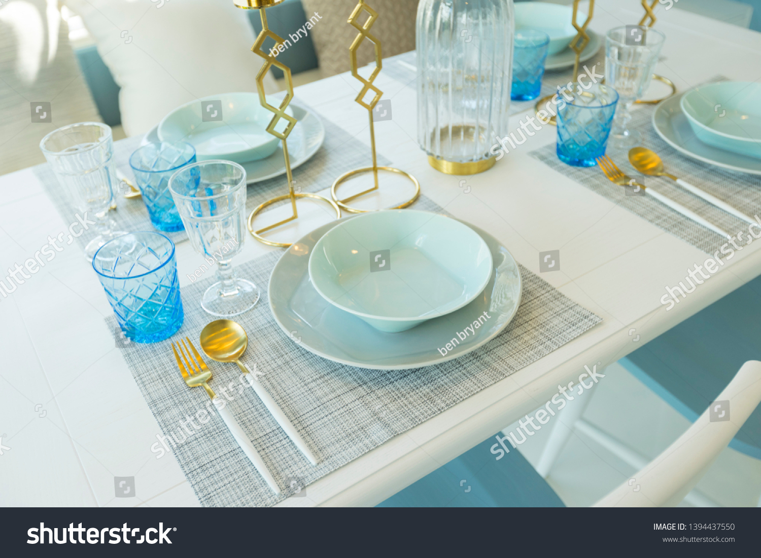 Pale blue plate setting on table with gold candle holder in home dining ...