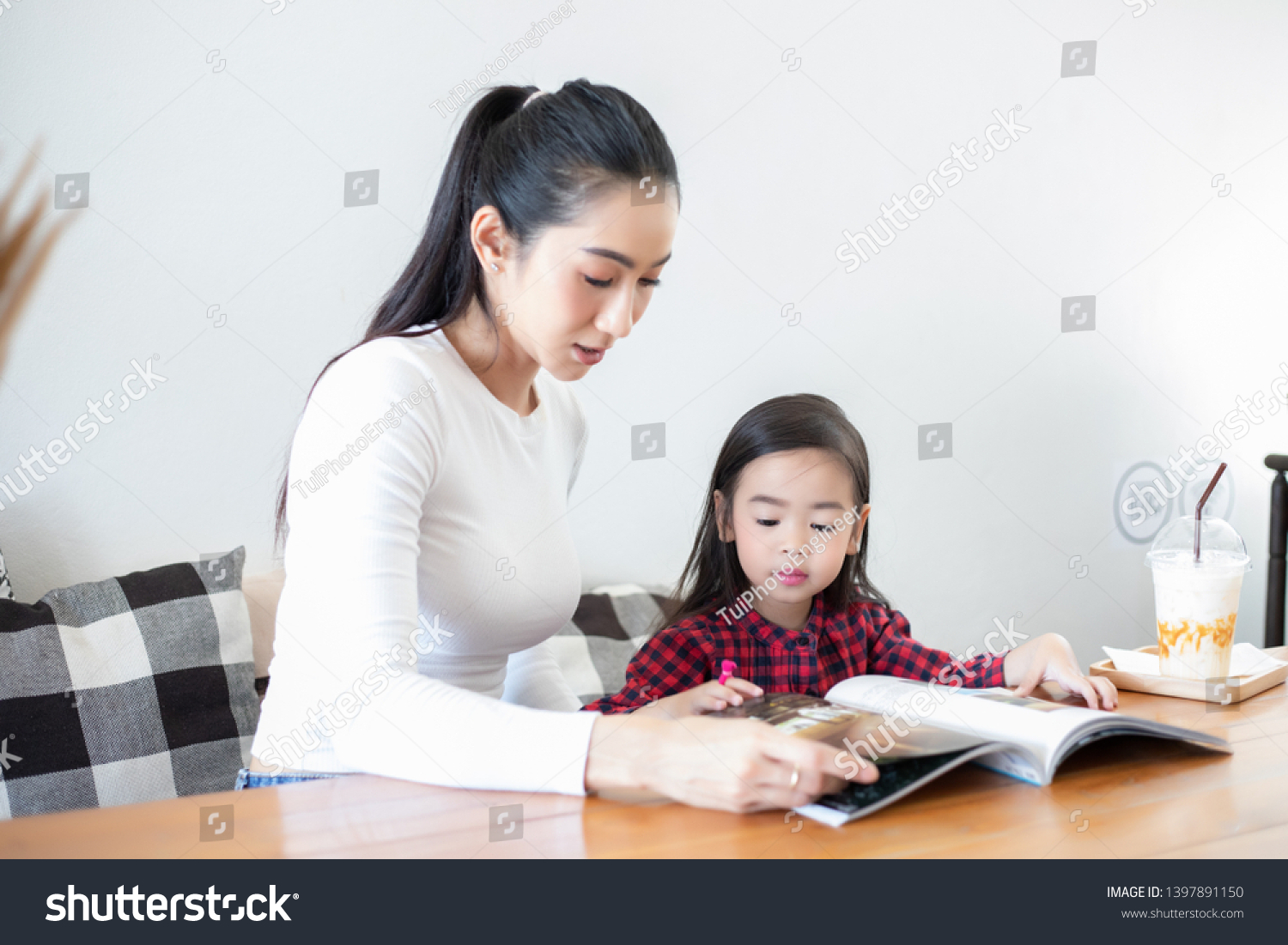 Mom is teaching her daughter to read a book.

