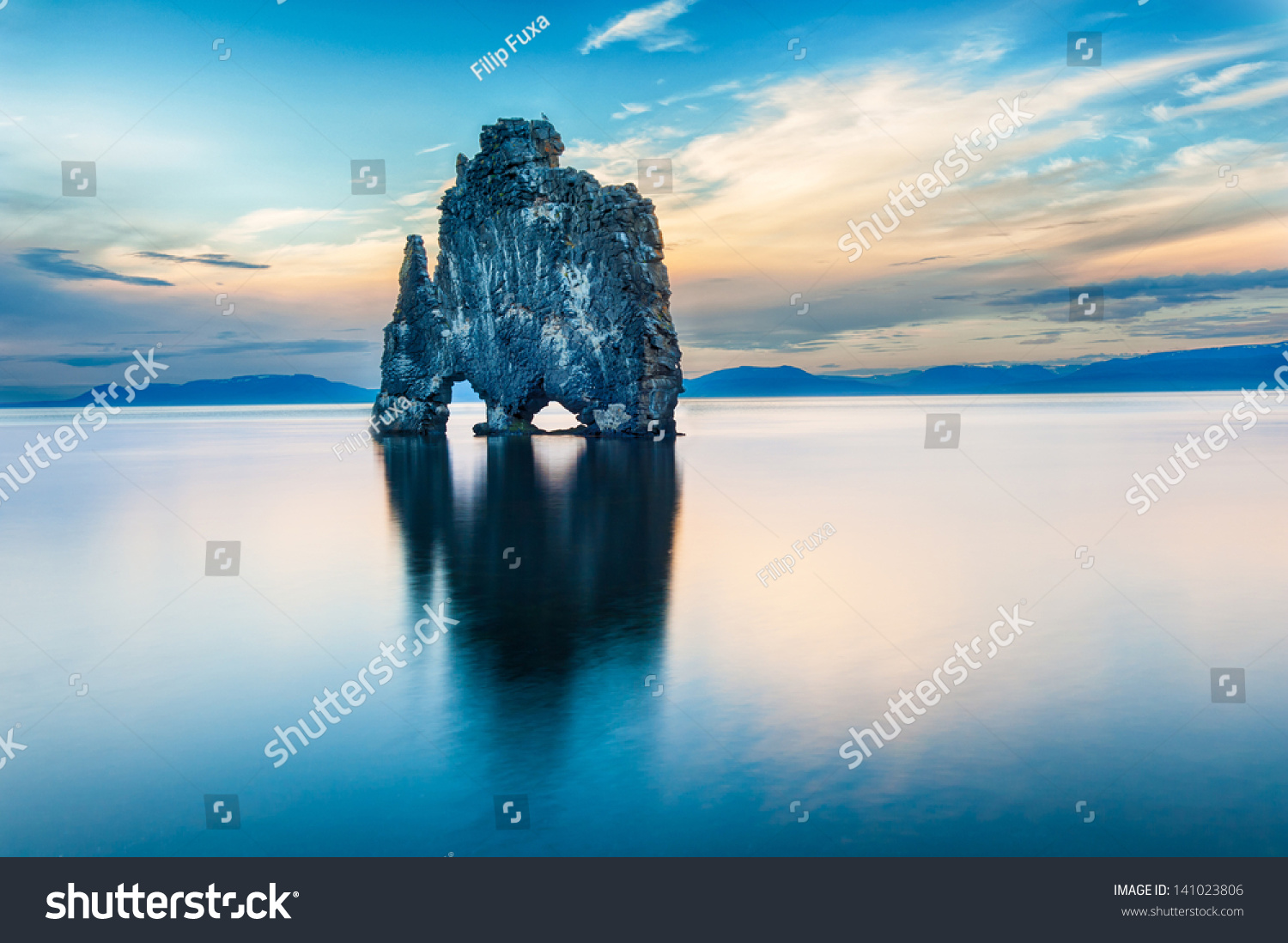 Hvitserkur is a spectacular rock in the sea on the Northern coast of Iceland. Legends say it is a petrified troll. On this photo Hvitserkur reflects in the sea water after the midnight sunset.