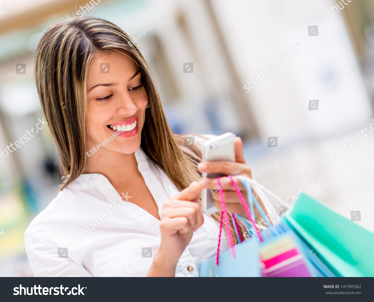 Happy woman using cell phone at a shopping center