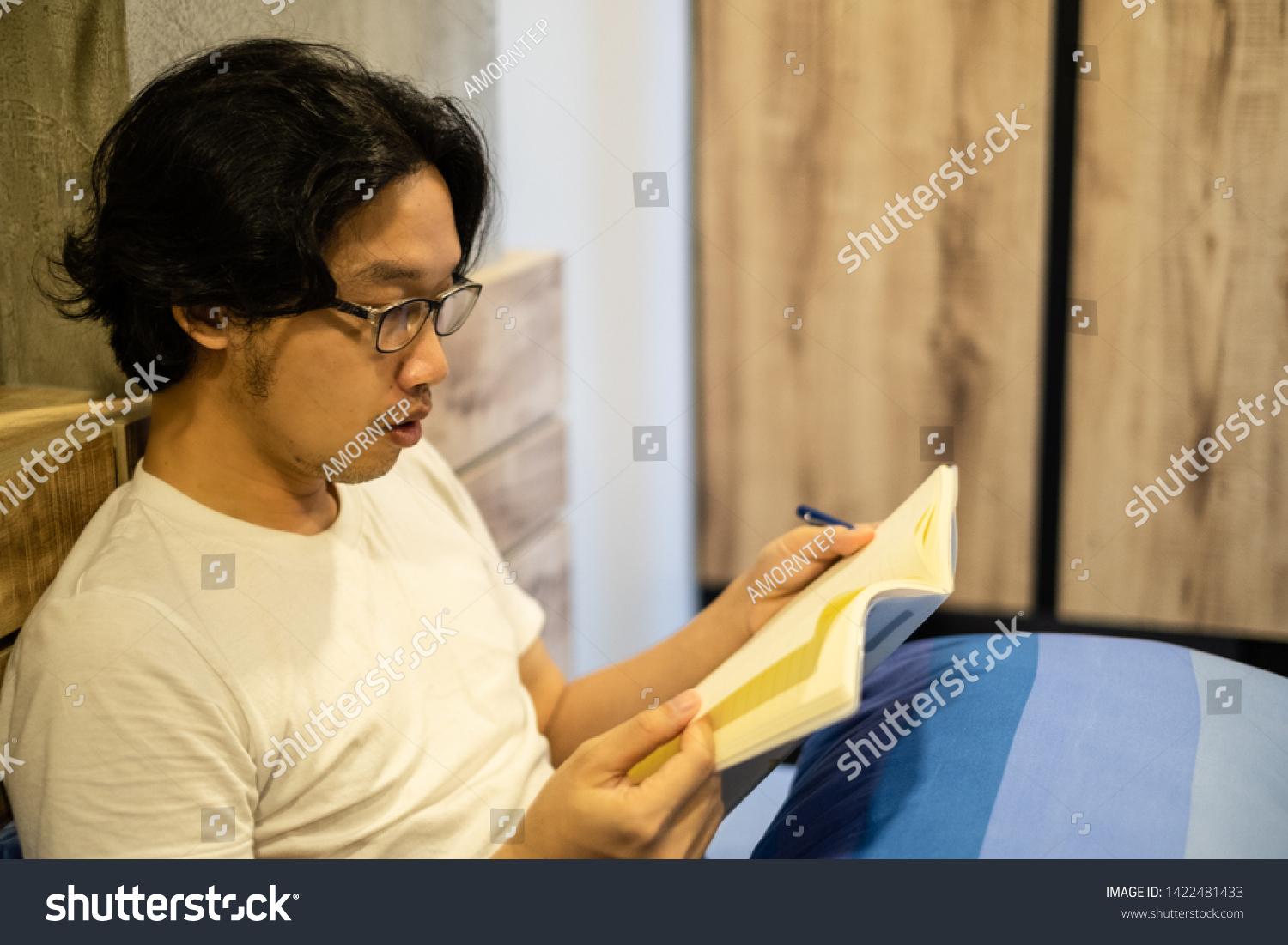 Asian handsome man reading a book on the bed