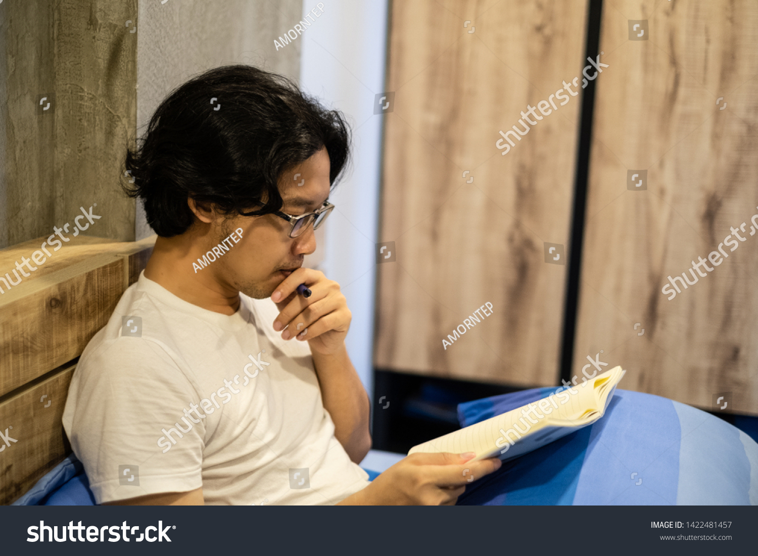 Asian handsome man reading a book on the bed