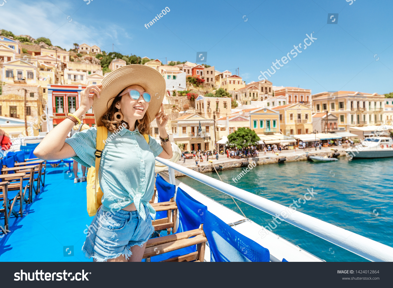 Asian girl traveler with backpack and hat enjoys a sea cruise on a open ship deck. Tourism and vacation in Greece and mediterranean sra. Transport and travel inspiration