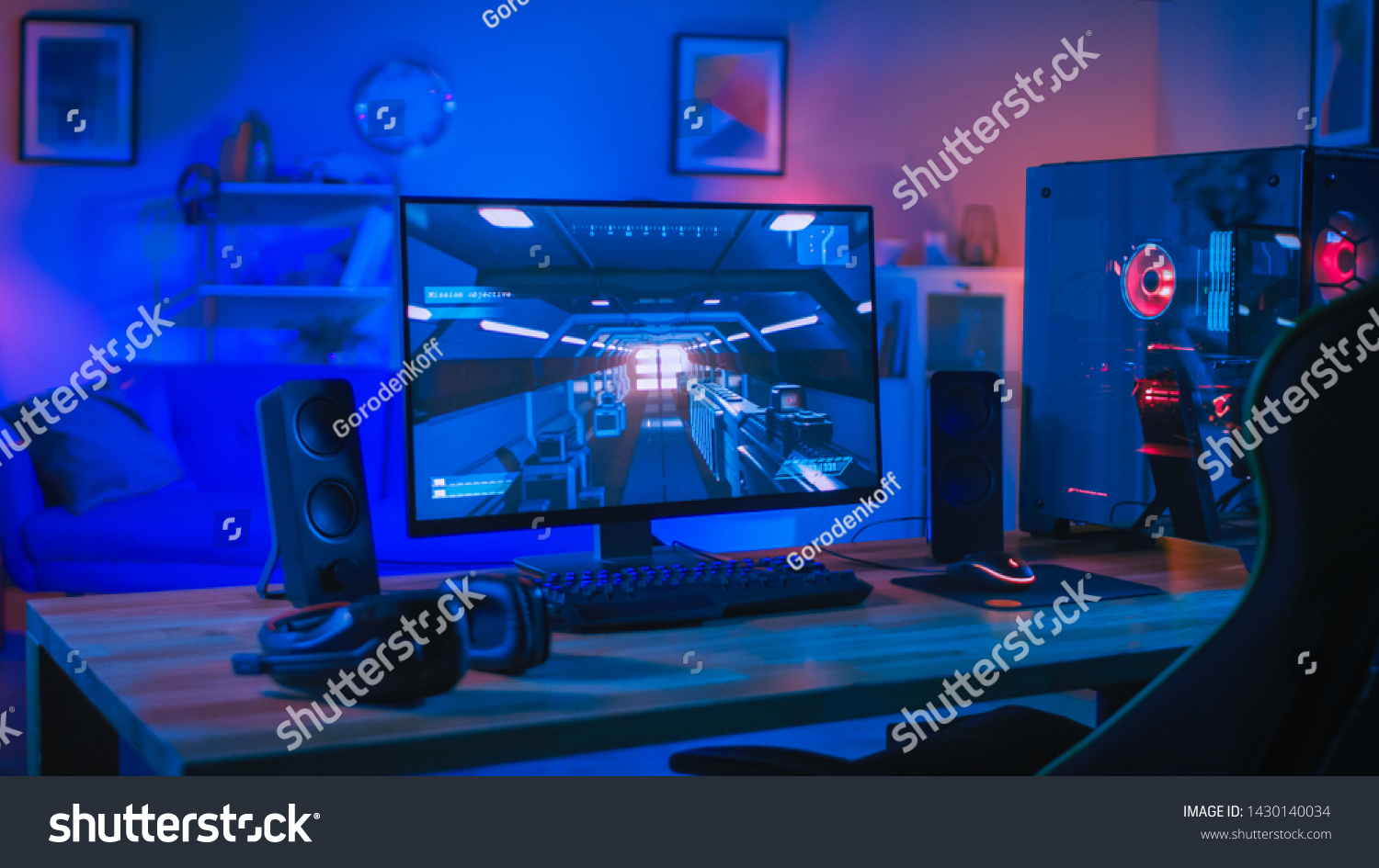 Powerful Personal Computer Gamer Rig with First-Person Shooter Game on Screen. Monitor Stands on the Table at Home. Cozy Room with Modern Design is Lit with Blue and Neon Light.