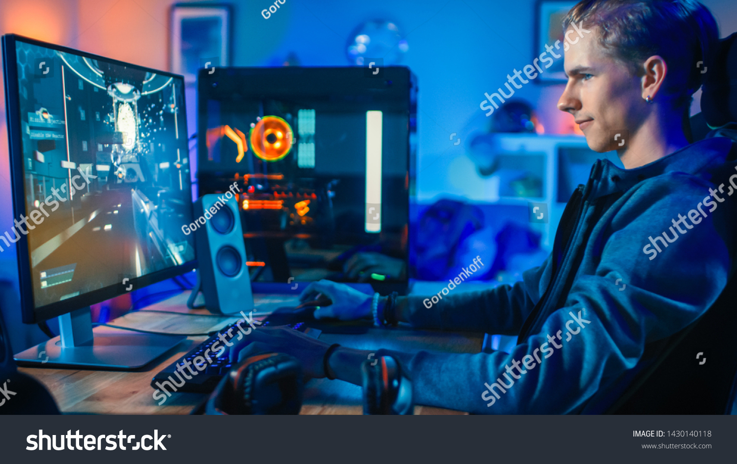 Cheerful Gamer Playing First-Person Shooter Online Video Game on His Powerful Personal Computer. Room and PC have Colorful Neon Led Lights. Cozy Evening at Home.