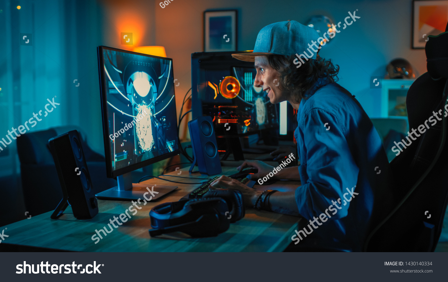 Professional Gamer Playing First-Person Shooter Online Video Game on His Powerful Personal Computer. Room and PC have Colorful Neon Led Lights. Young Man is Wearing a Cap. Cozy Evening at Home.