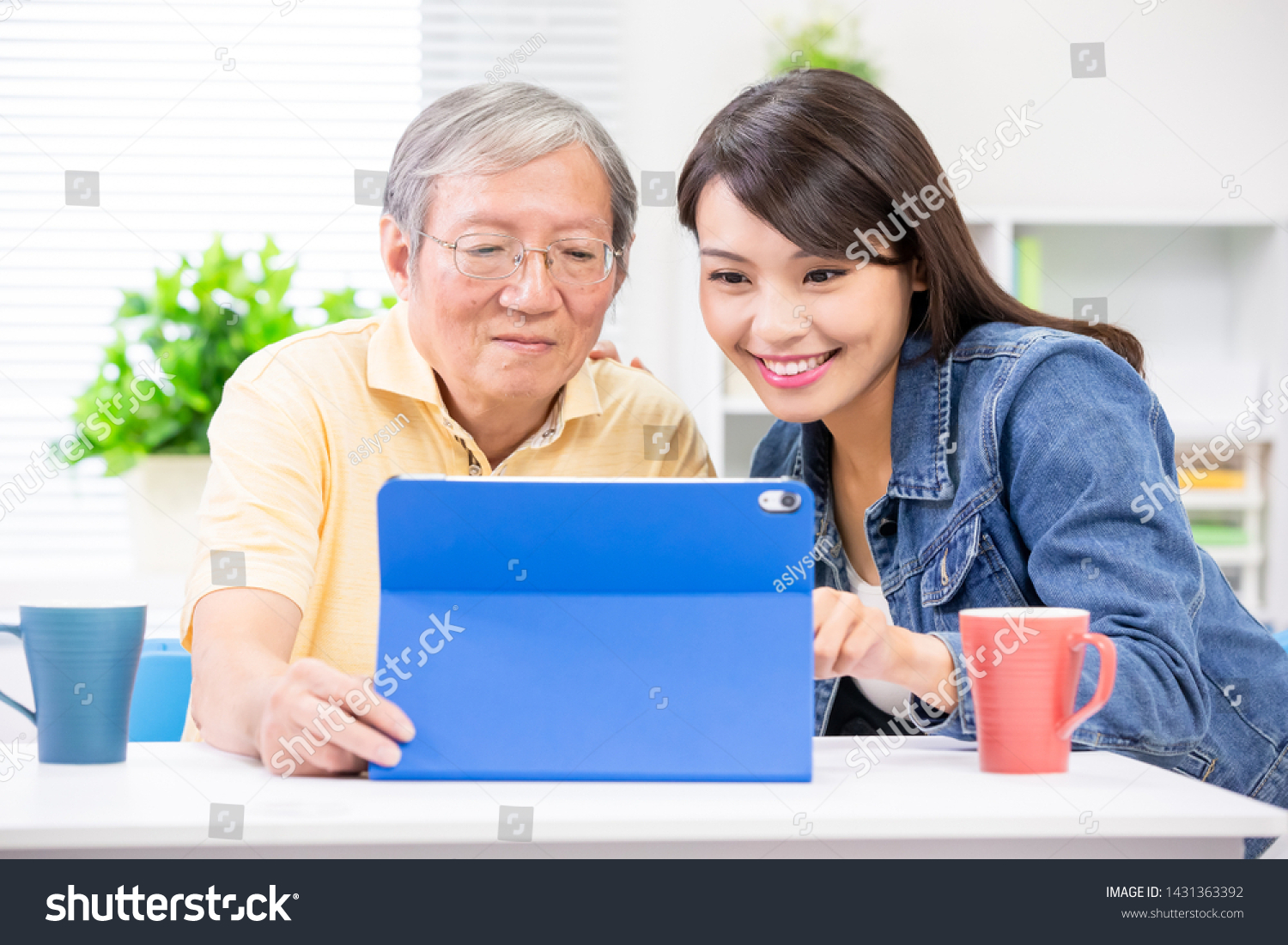 Young daughter teach elder father use tablet pc at home