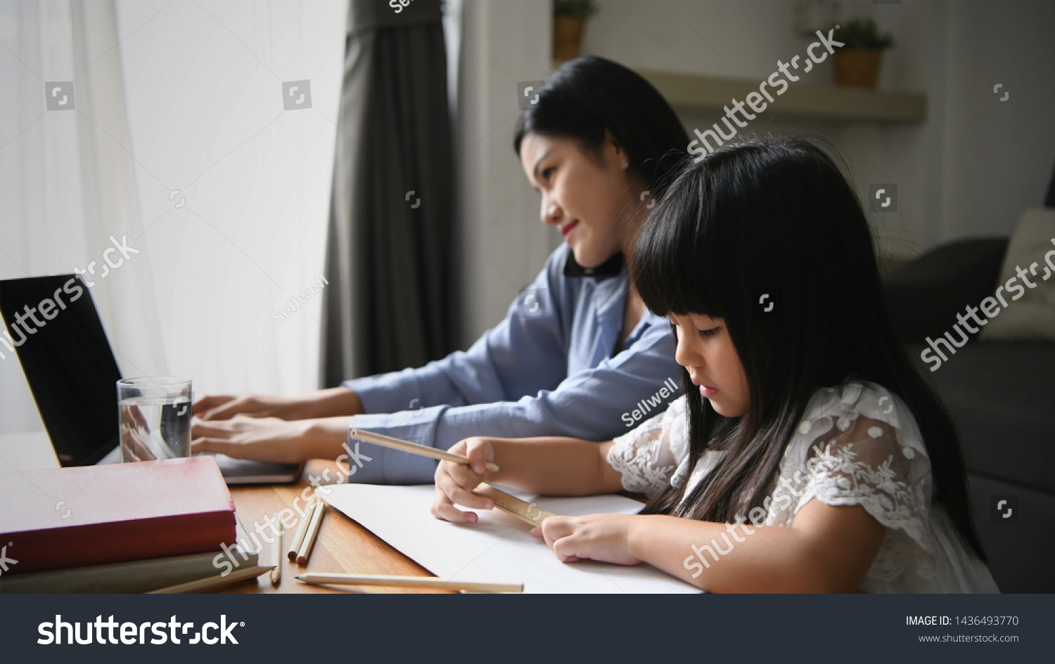 Family concept. Mom is working and taking care of her daughter too.