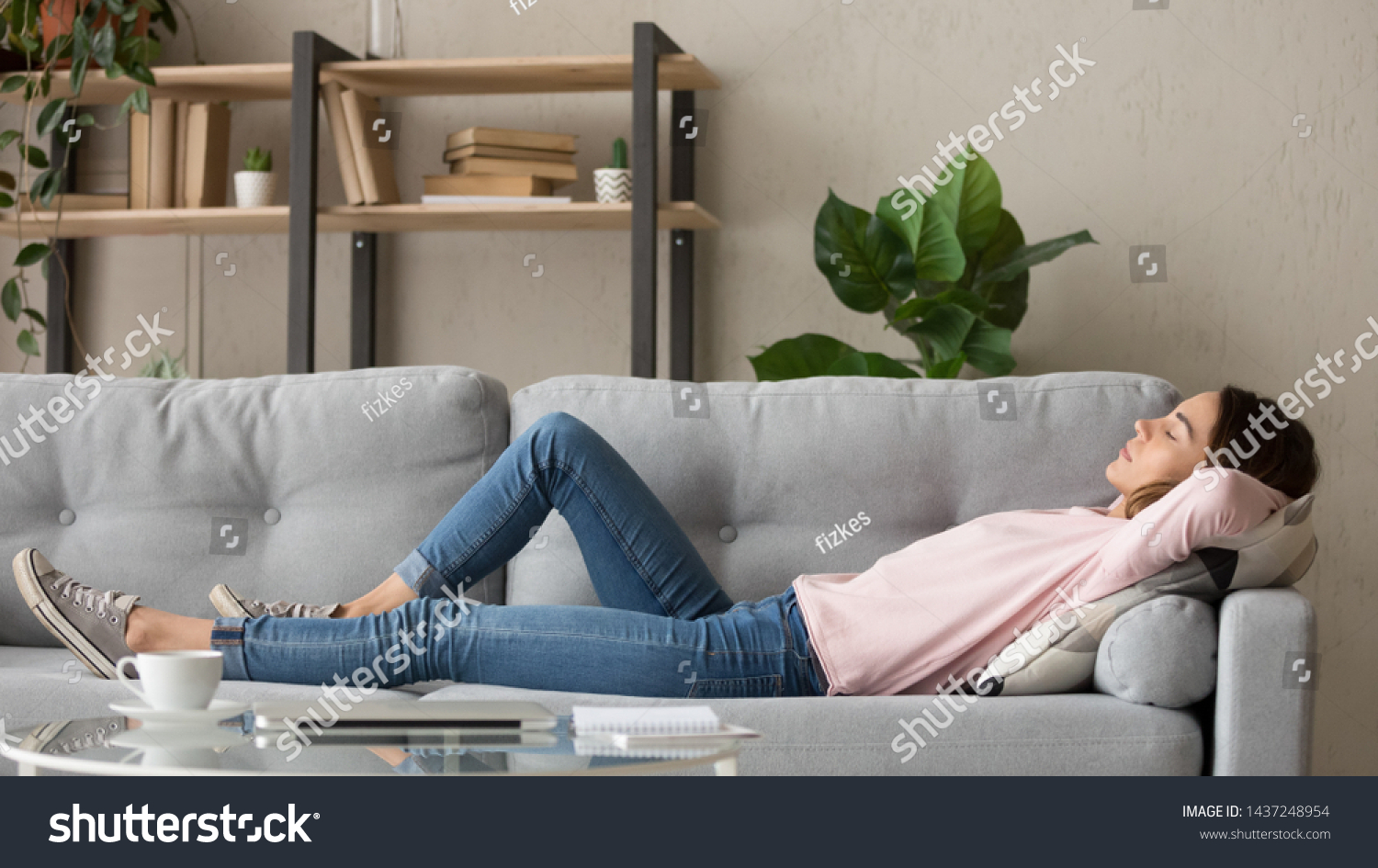 Tired young woman lying on cozy couch take nap daydreaming in living