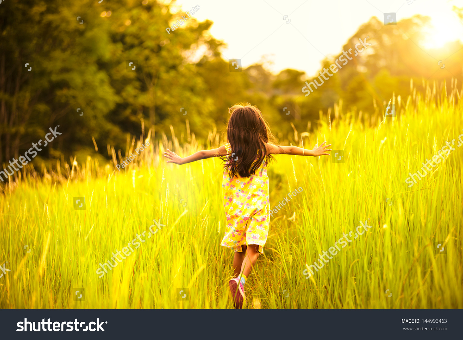 Little girl running on meadow with sunset