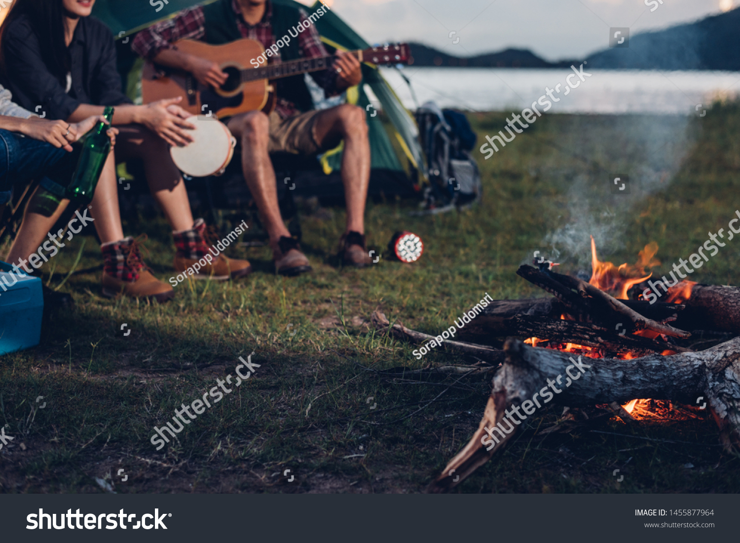 Camping tent camp in nature happy friends group night party bonfire and playing guitar together in summer at nature forest