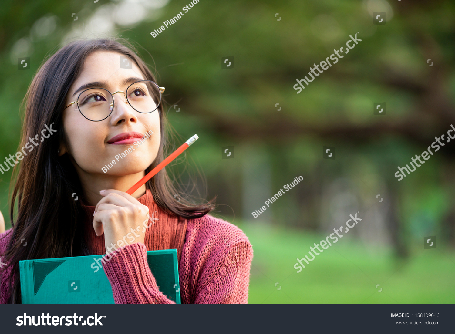 Young creative student girl thinking or planning future education while holding pencil in hand. Creativity idea and learning concept.