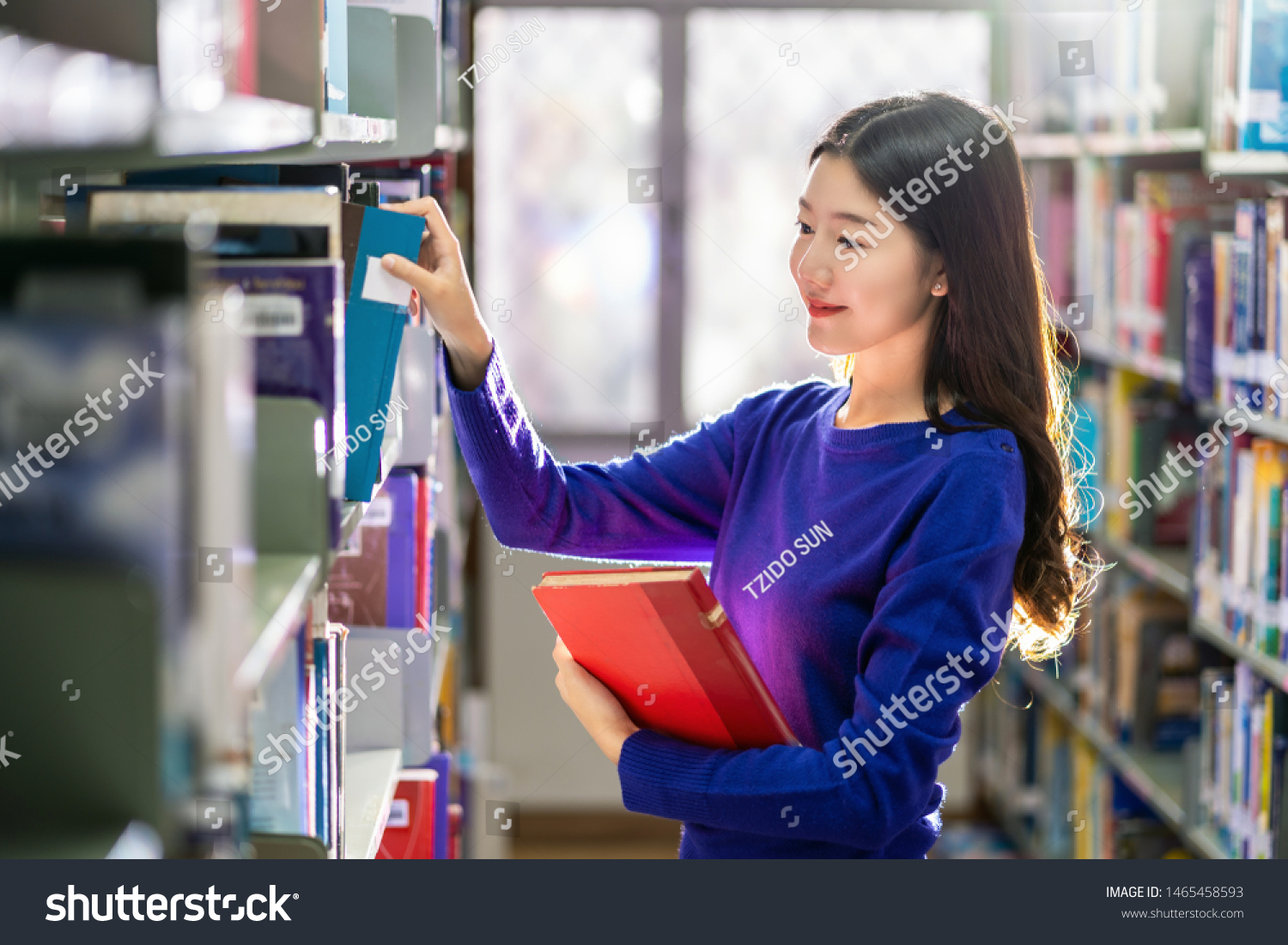 Asian young Student in casual suit searching the book from book shelf in library of university or colleage with various book background Back to school concept