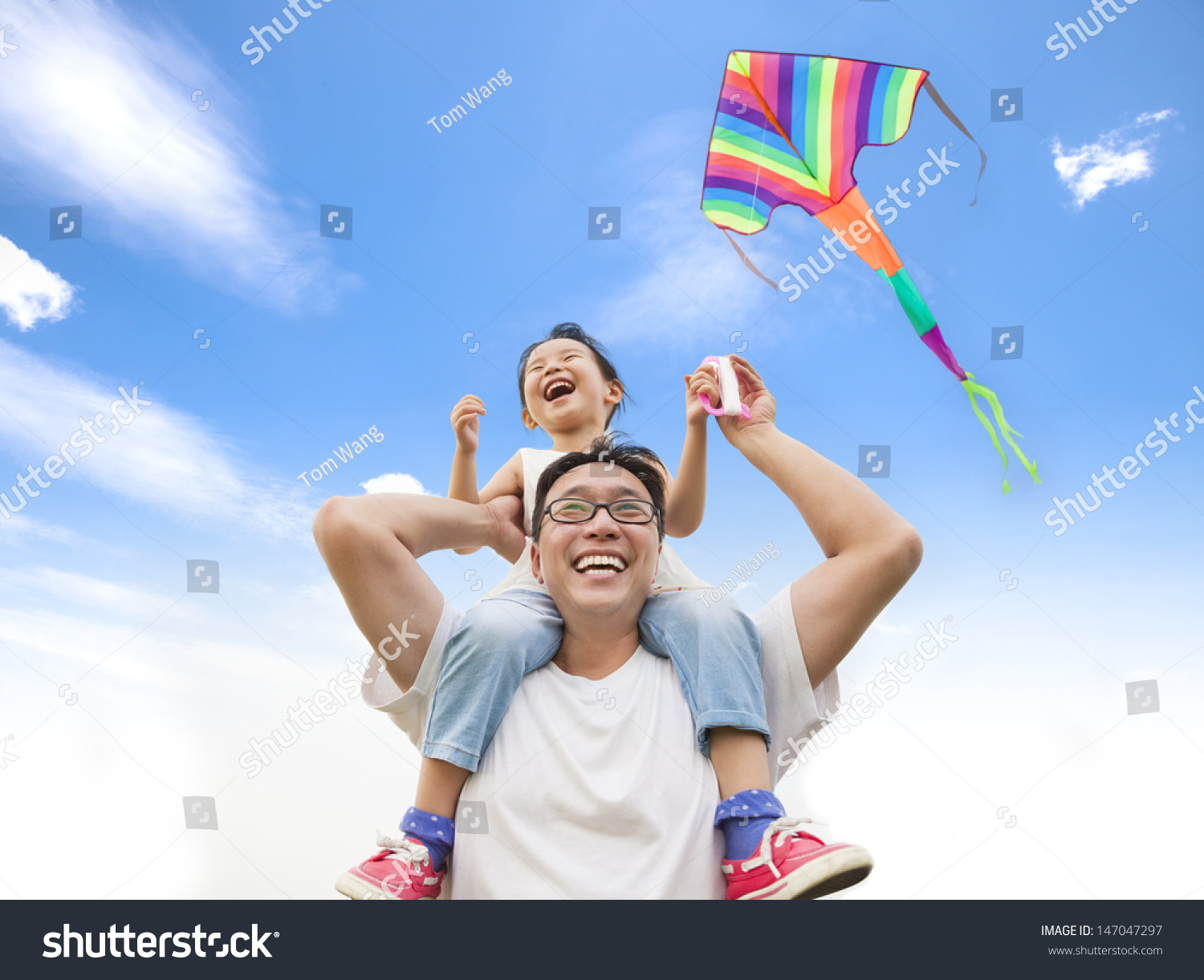 happy little girl on his father shoulder with colorful kite