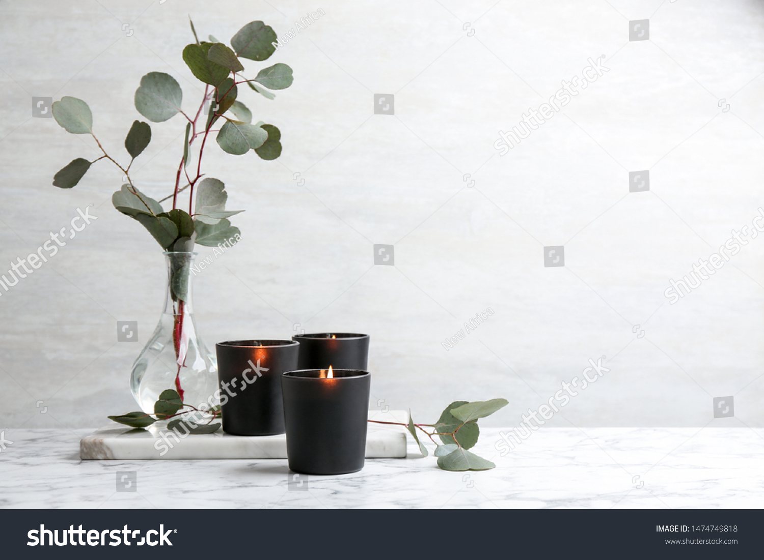 Burning candles and green branches on marble table  space for text