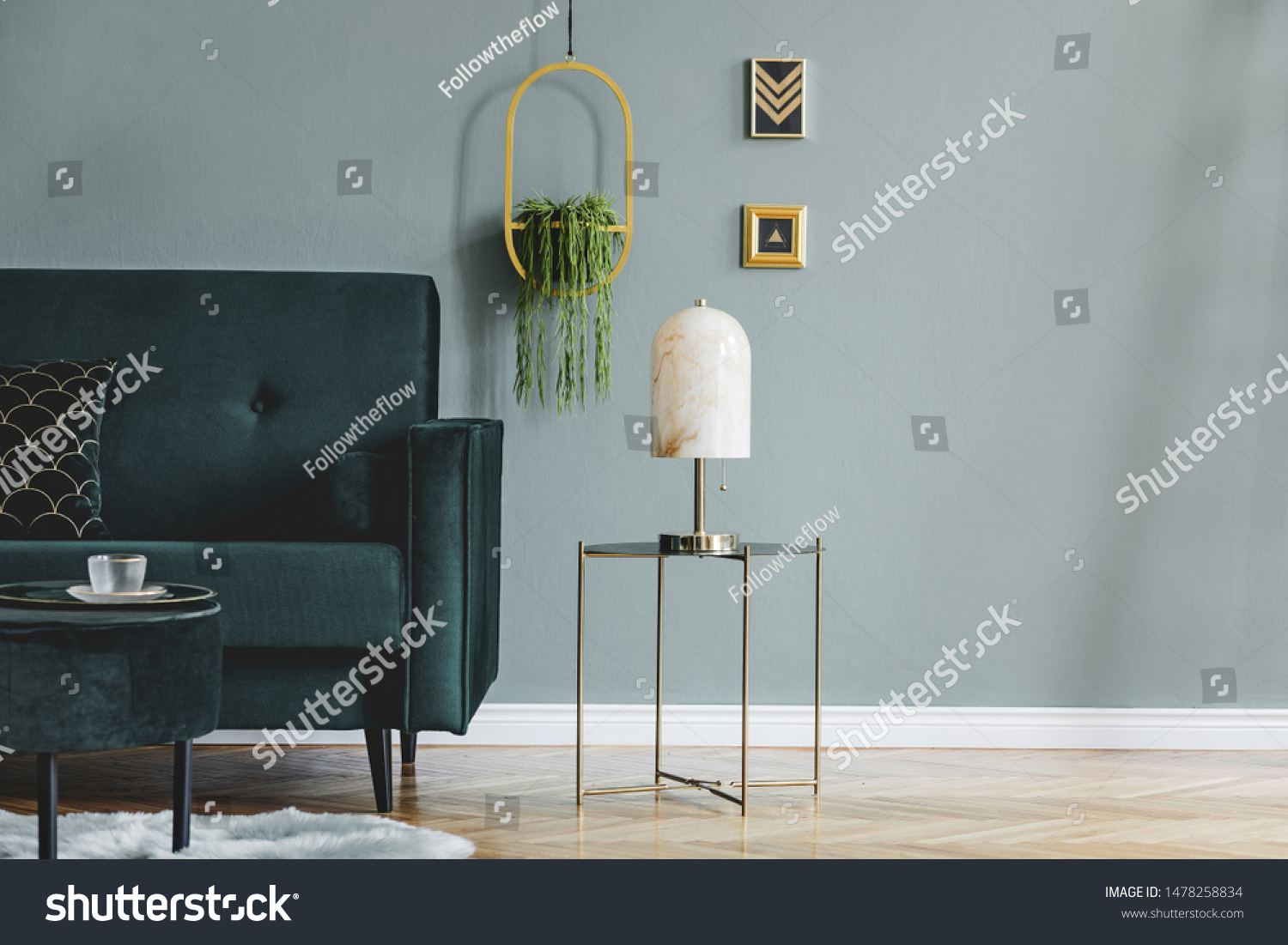 Design composition of living room interior with green vlvet sofa stylish coffee table marble table lamp pouf pillows hanging flowerbed plants and elegant accessories. Modern home decor. Template