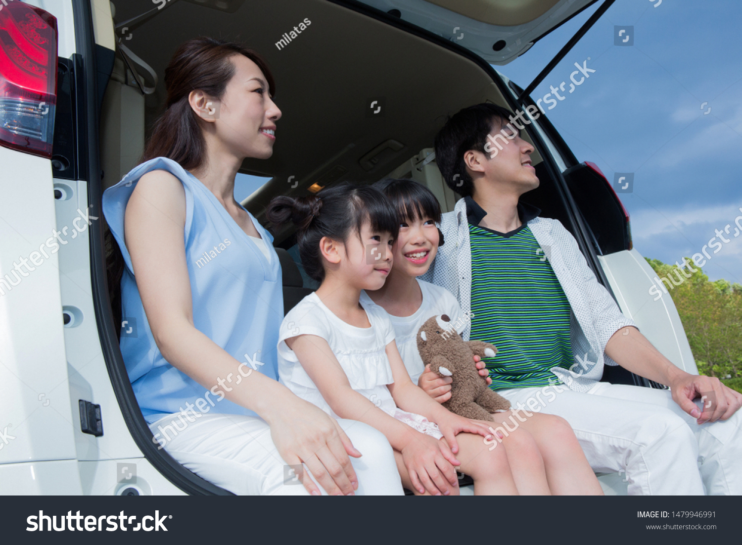 Family sitting in car trunk
