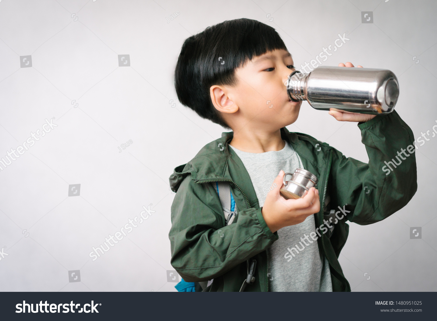 Studio portrait: Adorable little Asian boy drinks water from stainless steel reusable water bottle. Eco Friendly Lifestyle  Reduce Single Use Plastic  No Straw  Green Living  World Water Day.