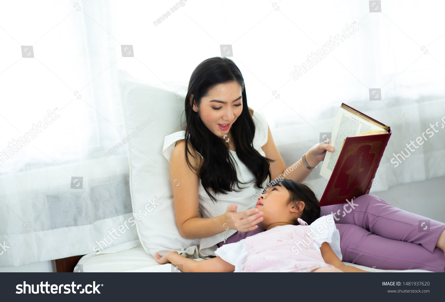 happy Little girl looking at book with her mother
