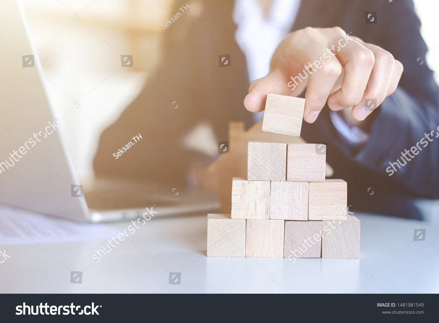 Closeup picture of a businessman placing wooden blocks to represent the peak of the boom to grow their business goals  financial statistics.