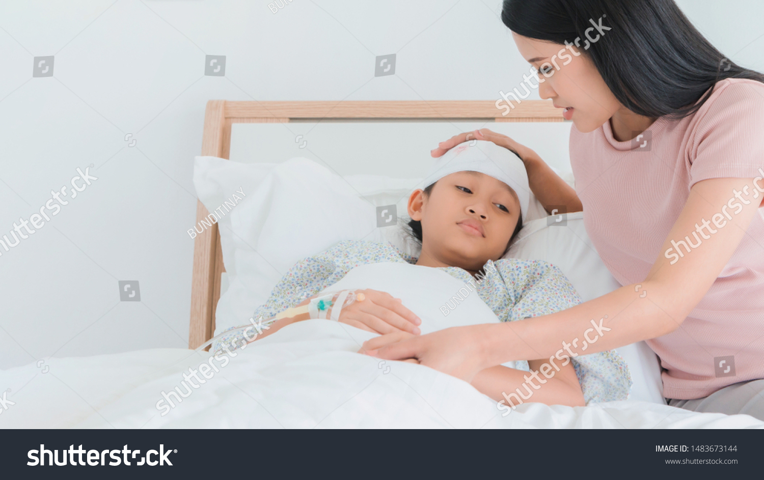 Asian mother caring for daughter injured at head and Stay on bed in the hospital.Concept of caring for the family.