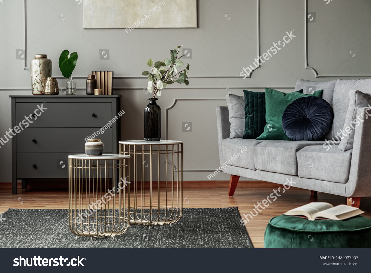 Two stylish small coffee tables with marble tops in front of elegant grey couch with emerald pillows